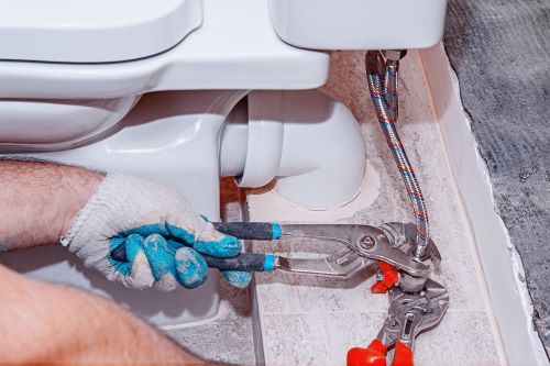 plombier Brétigny-sur-Orge - un plombier raccorde un flexible à des toilettes