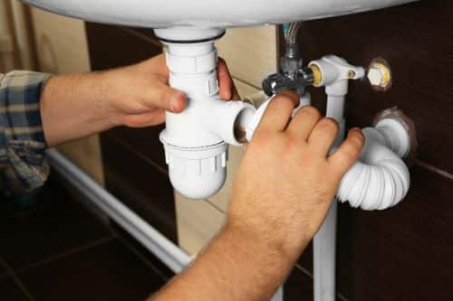 Plombier Prémesques - Un plombier répare un siphon.