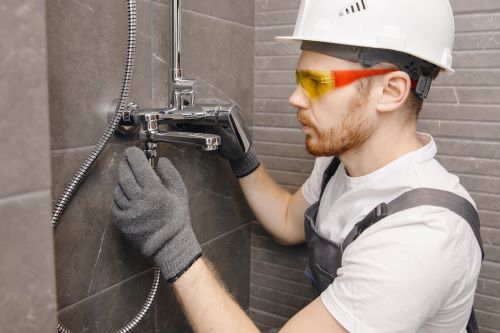Plombier Saint-Fons - Un plombier installe un mitigeur de douche.