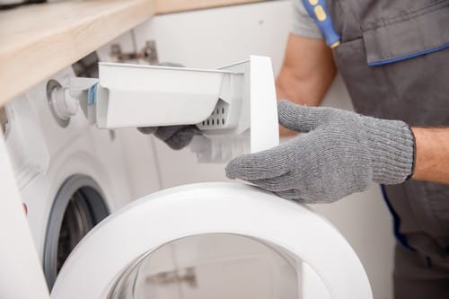 Plombier Harnes - Un plombier répare une machin à laver