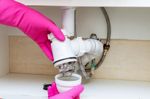 Plombier Montpellier - Un plombier nettoie un siphon.
