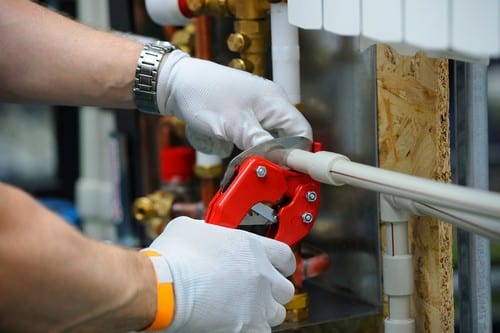 plombier Beaucaire - un artisan découpe un tuyau en multicouche