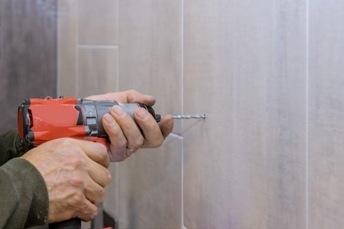 plombier Sorgues - un artisan perce un trou dans un mur
