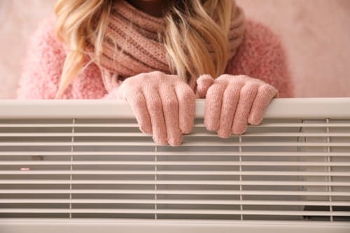 chauffagiste Savigny-le-Temple - Une femme se réchauffe les mains sur un radiateur
