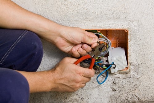 Electricien Le Haillan - mains d'un homme qui répare des câbles électriques