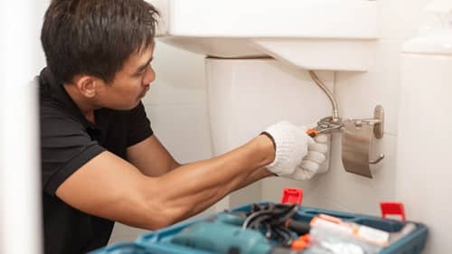 Plombier Vernouillet - homme qui règle une robinetterie de lavabo