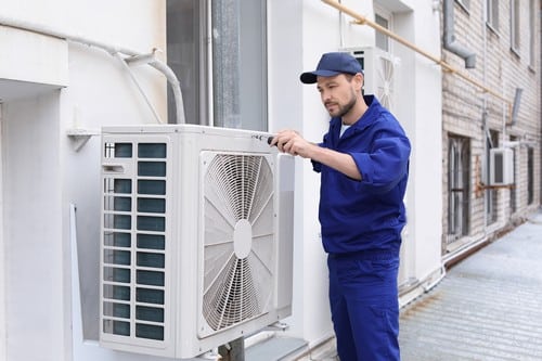 Climatisation Clichy - homme qui règle un climatiseur en extérieur
