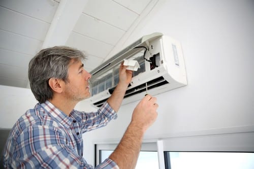 Climatisation Paris 19 - homme qui règle un climatiseur au plafond