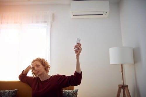 Climatisation Agde - les bons artisans - femme qui règle sa climatisation