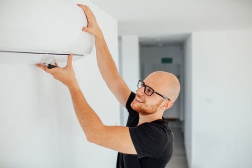 Climatisation Louvres - homme qui règle un climatiseur au plafond