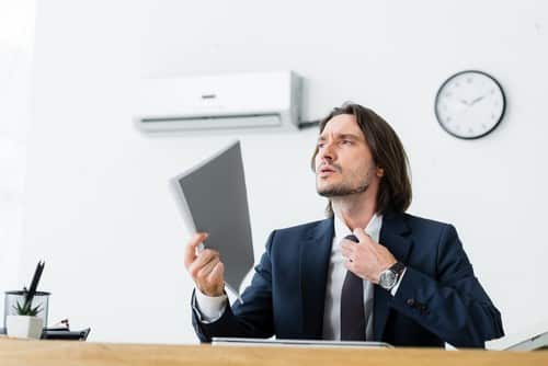 Climatisation Entraigues-sur-la-Sorgue - homme assis à son bureau en dessous d'un climatiseur